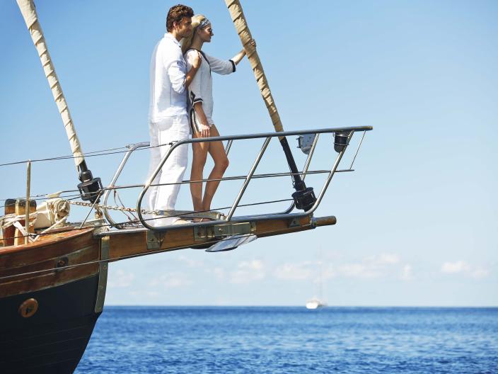 couple stand on front of boat
