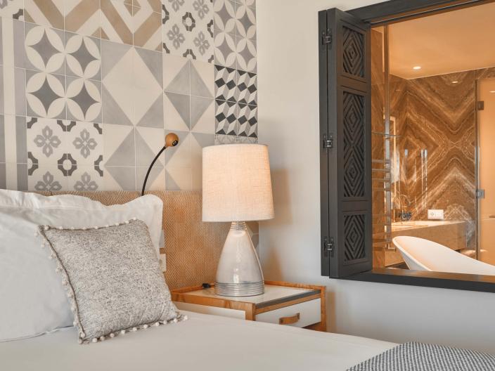 Bedroom with king bed and nightside table with a window to the bathroom open