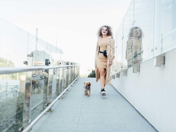 woman walking a small dog along a glass enclosed walkway
