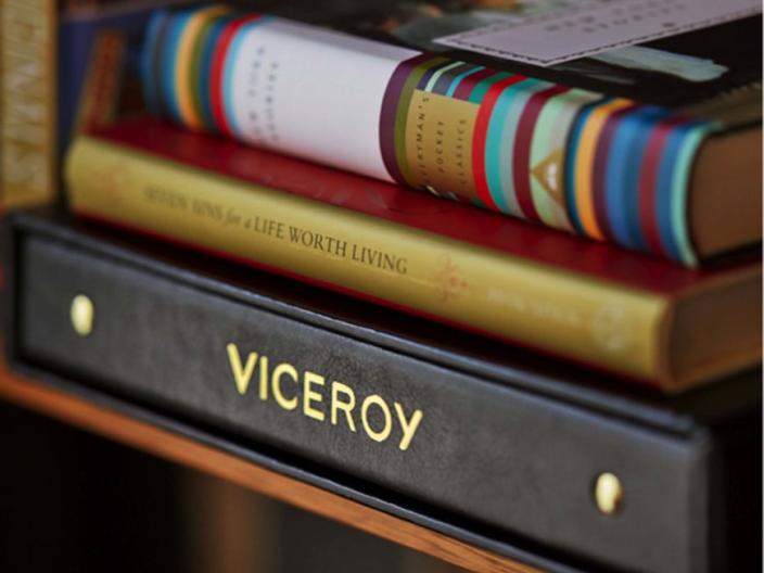 A stack of two books on top of a black binder labelled "Viceroy" in gold embossing.