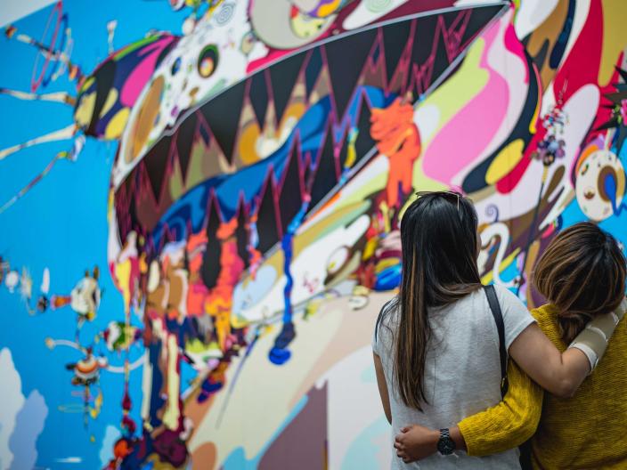 Two visitors to Chicago, arm in arm, appreciate a large street art mural