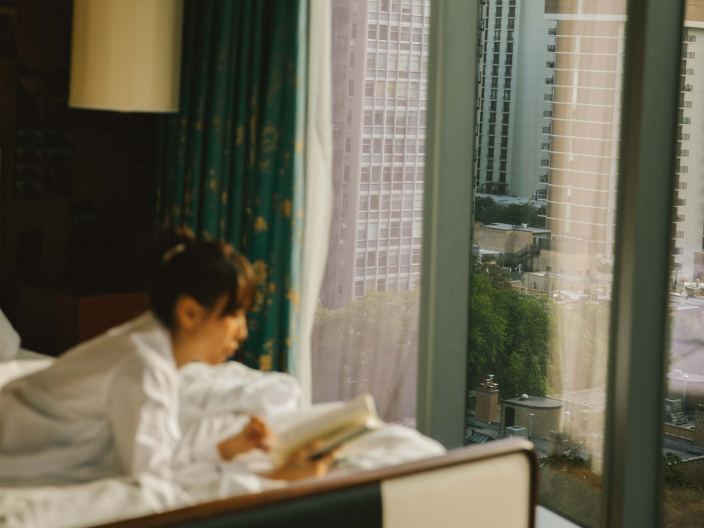 A woman laying on a bed reading a book at Viceroy Chicago