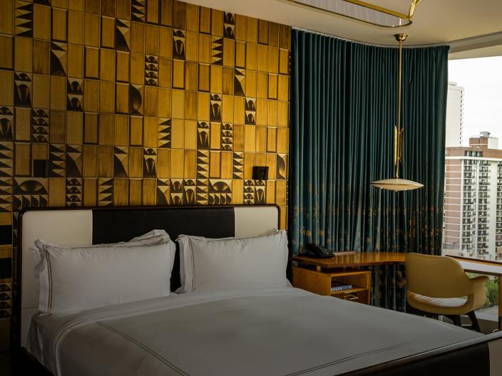 A chique hotel room with a patterned yellow accent wall at Viceroy Chicago