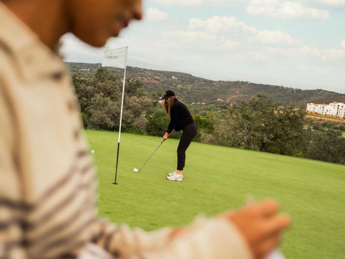 A woman putting and a woman taking score will golfing at Viceroy Ombria Algarve