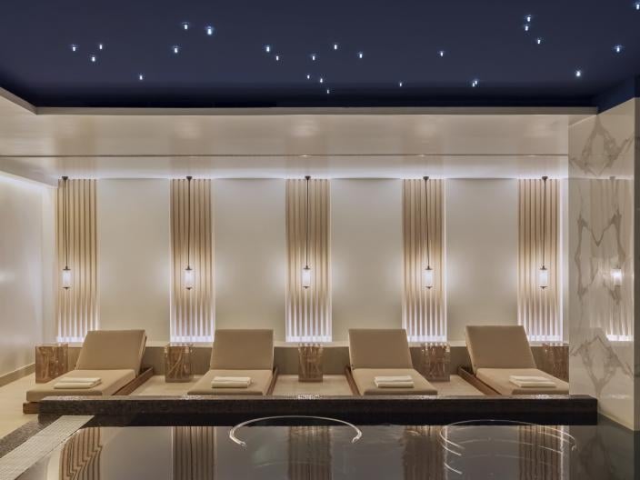 A row of reclining chairs in front of a reflecting pool at the Viceroy Kopaonik Serbia spa