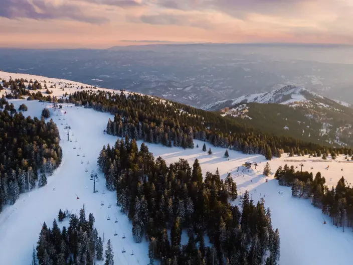The ski slopes at Viceroy Kopaonik Serbia, with a mountain range in the background under a pink and orange sky