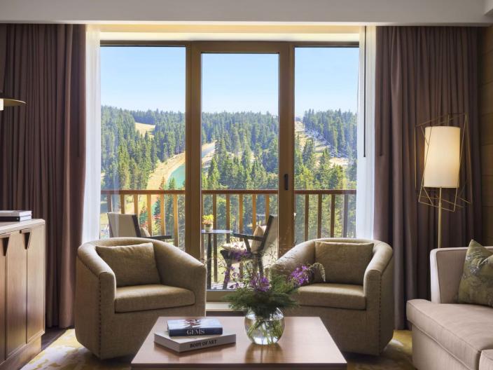 The living space with a TV, couch, and two chairs in a suite at Viceroy Kopaonik Serbia
