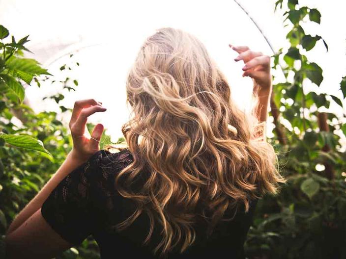 A woman runs her hands through her hair in a field