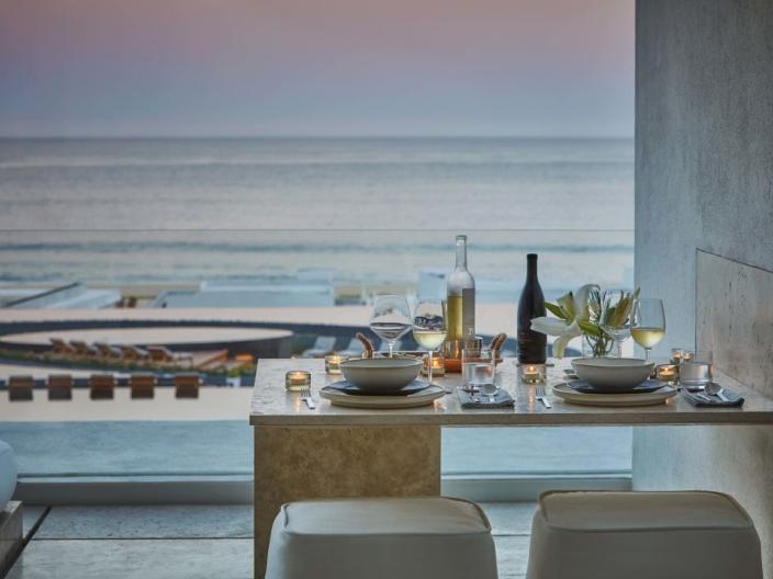 A patio table with food and wine, looking out on the ocean