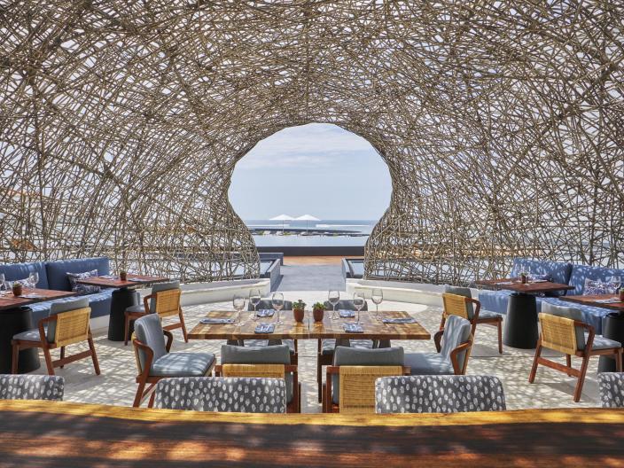 The dining room of Nido restaurant at Viceroy Los Cabos, an outdoor dining terrace under a nest-like dome roof made of woven sticks