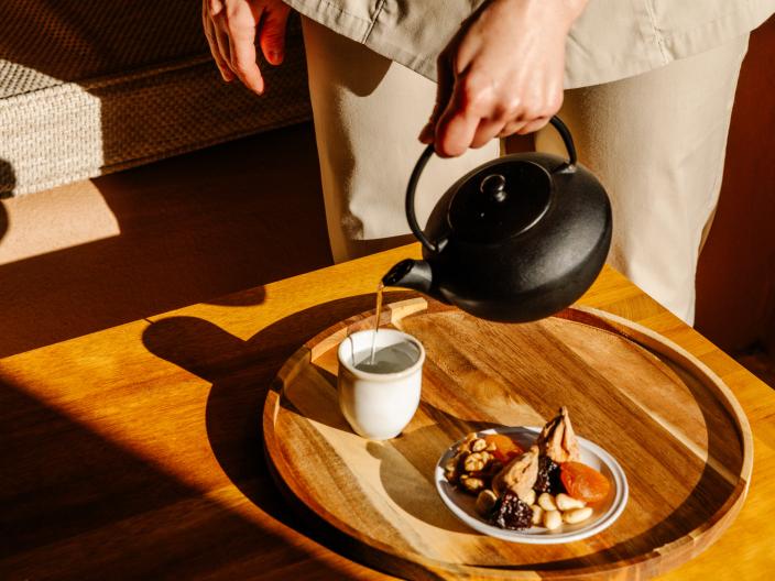 A person pouring a personal pot of tea