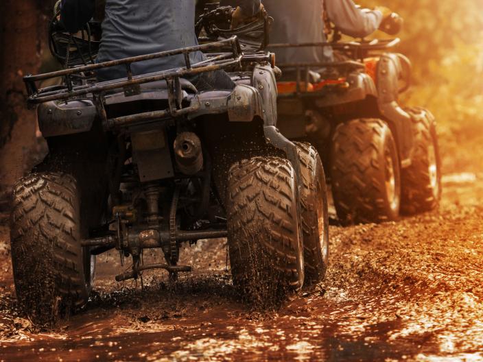 All terrain vehicles driving down a muddy path