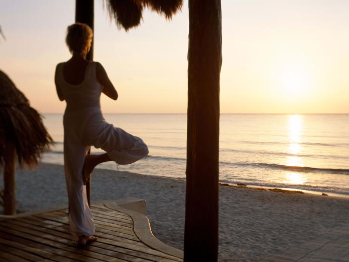 A woman doing yoga at sunset at the beach