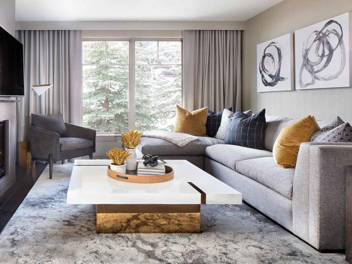 The large living area with a white marble coffee table, couch, and a television at Viceroy Snowmass