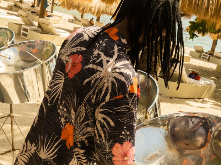 A man plays steel drums on a beach in St. Lucia, surrounded by beach huts