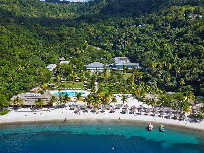 An aerial view of a beachfront resort with a mountain range behind it