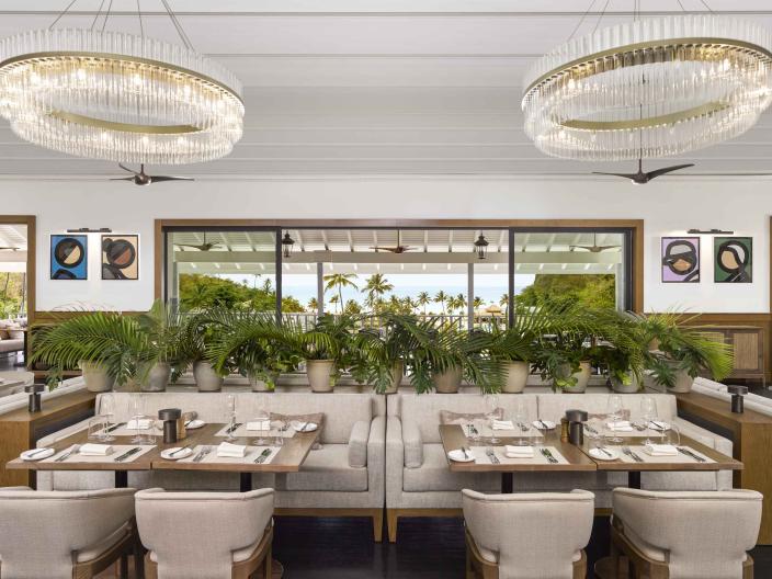 The dining room of Saltwood Restaurant at Sugar Beach, with several booths and a view of the beach outside