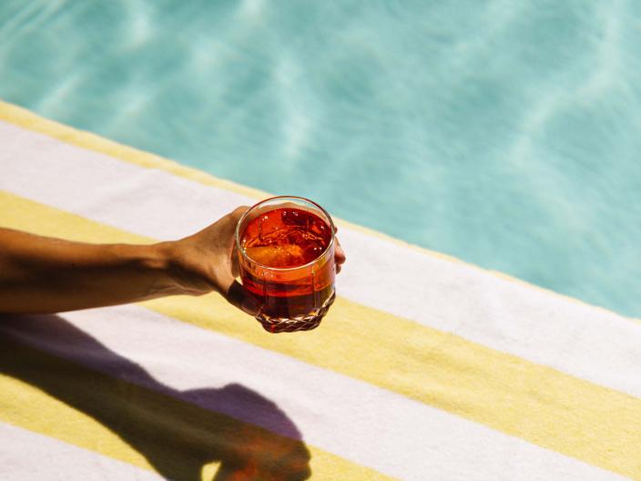 A hand holding a cocktail at a pool