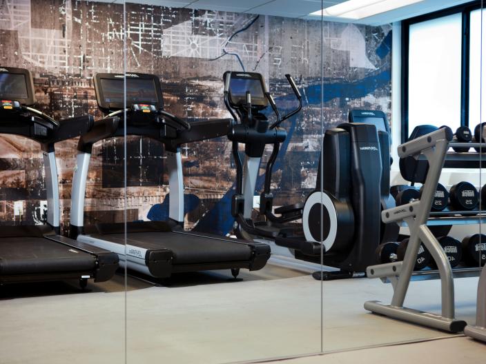 The fitness centre at Viceroy Washington DC, with a row of treadmills and a rack of free weights
