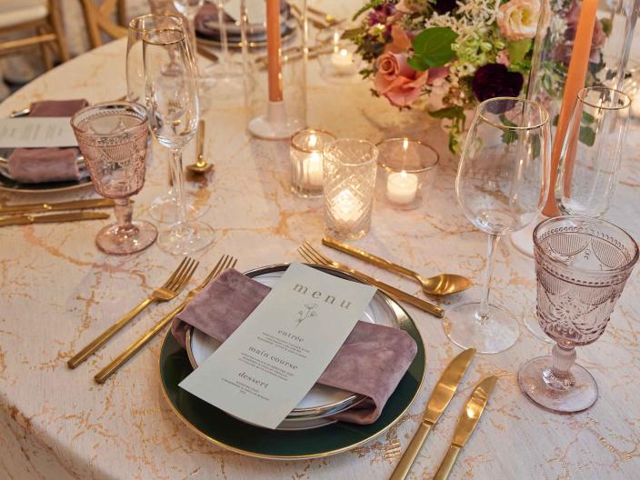An elegant place setting with gold cutlery and floral centerpieces on a white tablecloth at Viceroy Washington DC