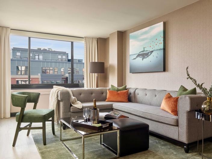 A room at Viceroy Washington DC with an L-shape couch, coffee table, chair, and balcony
