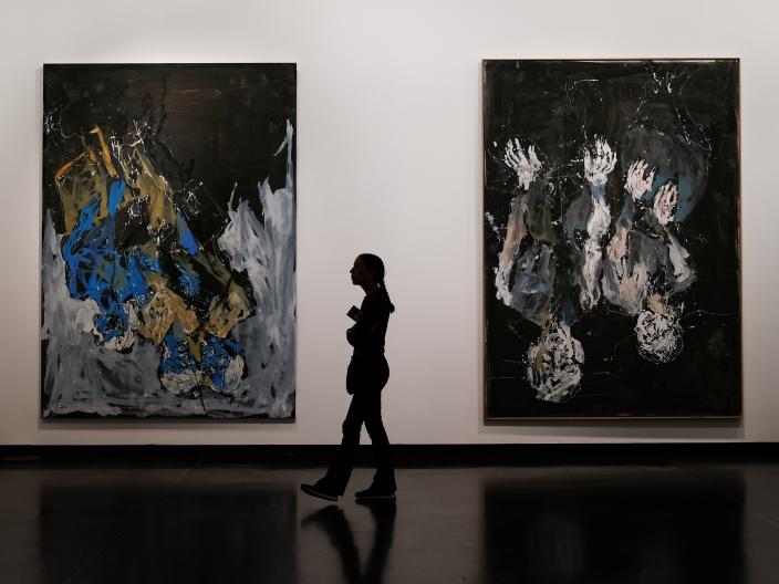A woman walking between two large paintings in the national museum in Washington