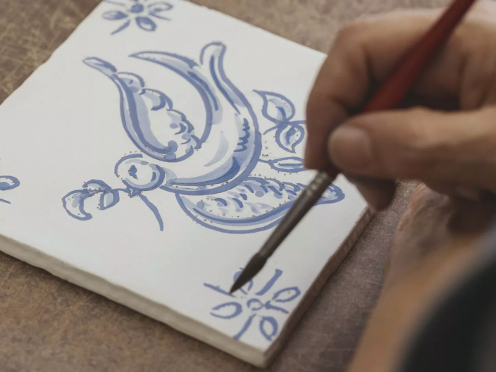 A person painting a blue bird in a greek tile style at Ombria Algarve