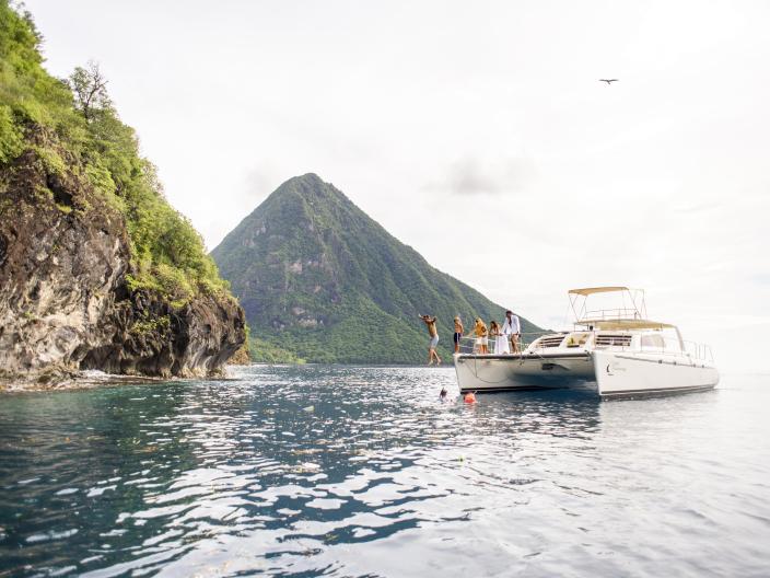 person jumps into water off a sail boat
