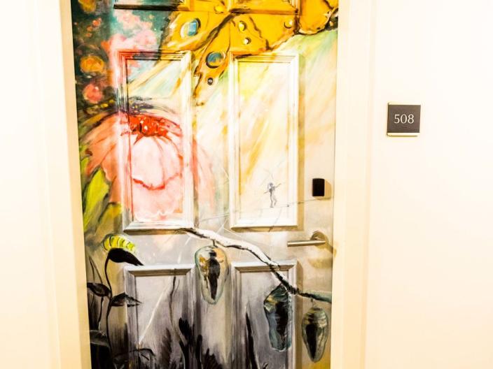 A hotel door painted with a flower and butterfly motif