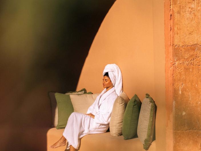A woman sits in the sun outside of a spa