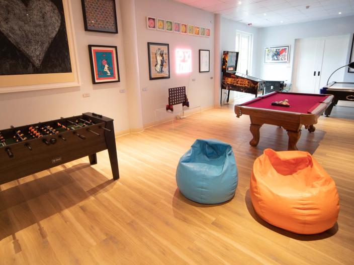 A bright kids play room with arcade games, a foosball table and two bean bag chairs among other amenities