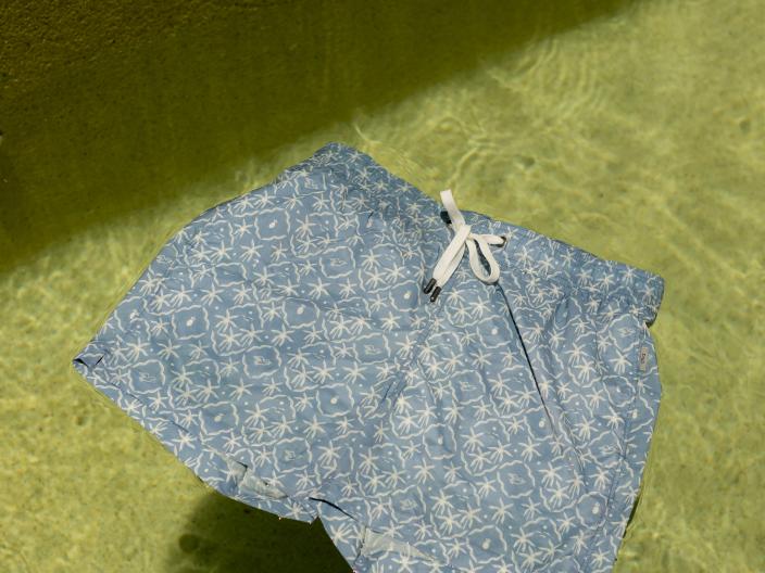 A pair of Onia x Viceroy swim trunks float on crystal clear water.