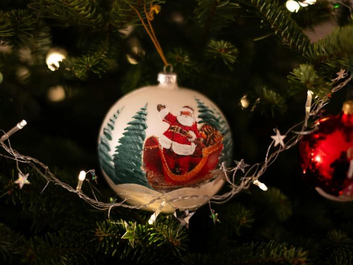 A Santa Claus ornament hangs on a Christmas Tree