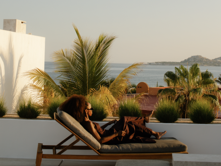 a woman relaxing on a lounge chair on a ocean-view terrace at a Viceroy Resort