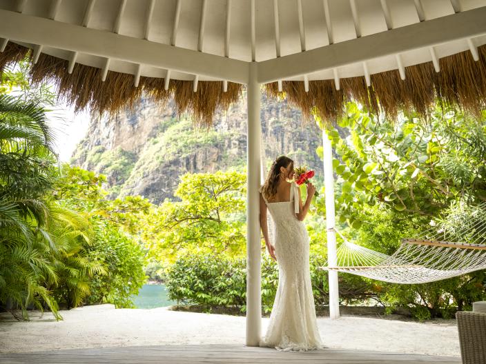 Une femme debout, un bouquet à la main, vêtue de sa robe de mariée