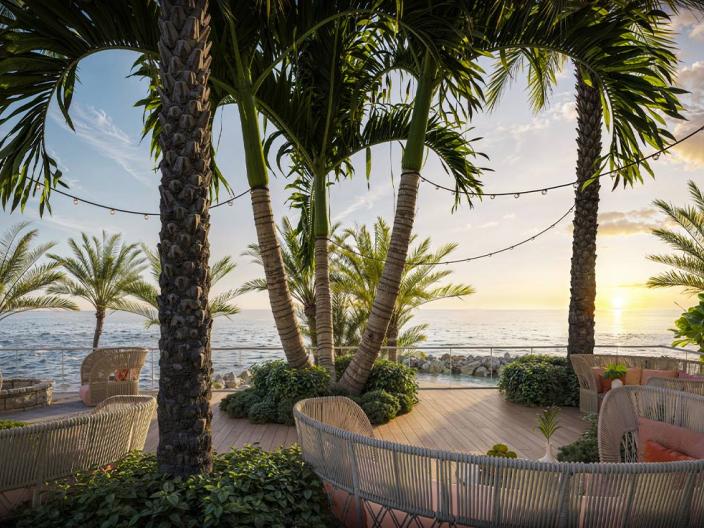 Espace de détente extérieur au charme tropical, agrémenté de palmiers et offrant une vue sur l'océan au coucher du soleil.