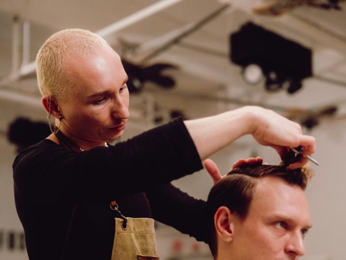 Timur a cortar o cabelo a um homem sentado na cadeira do salão 