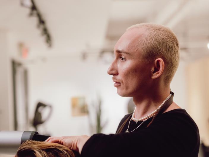 Timur a cortar o cabelo a um homem sentado numa cadeira de salão de cabeleireiro