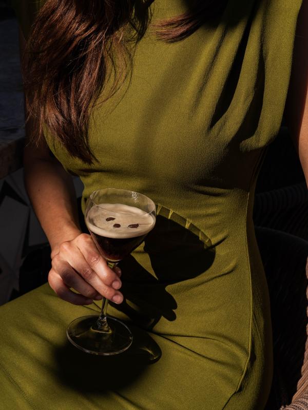woman in green dress holds an espresso martini