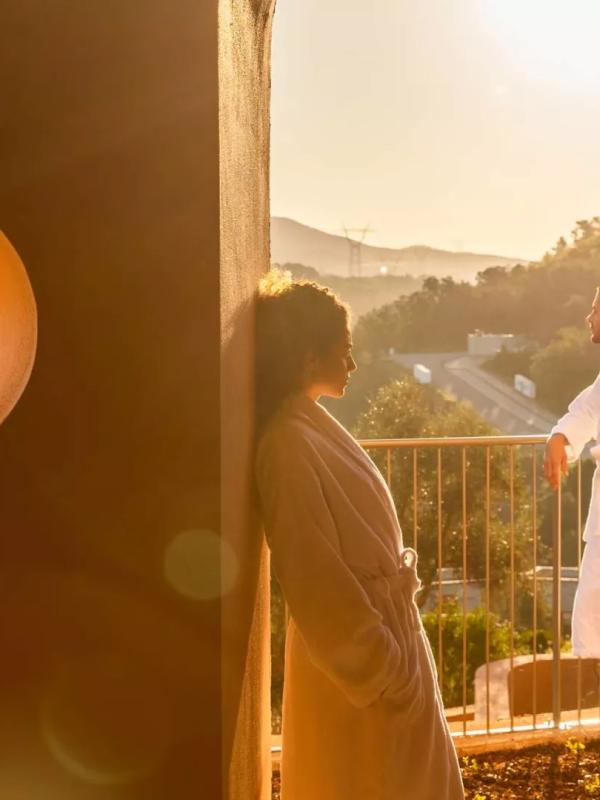 two people stand in white robes on balcony