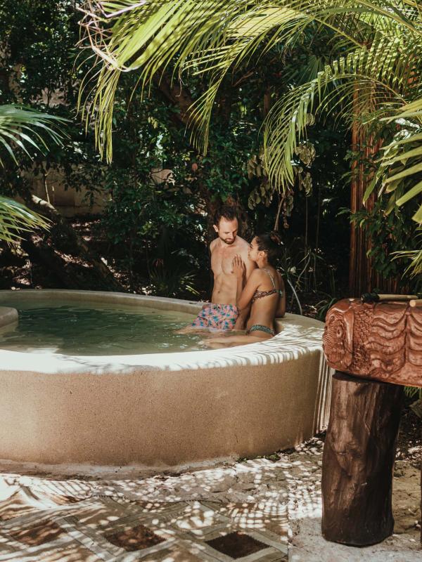 Una pareja está sentada en la piscina, rodeada de hojas de palmera
