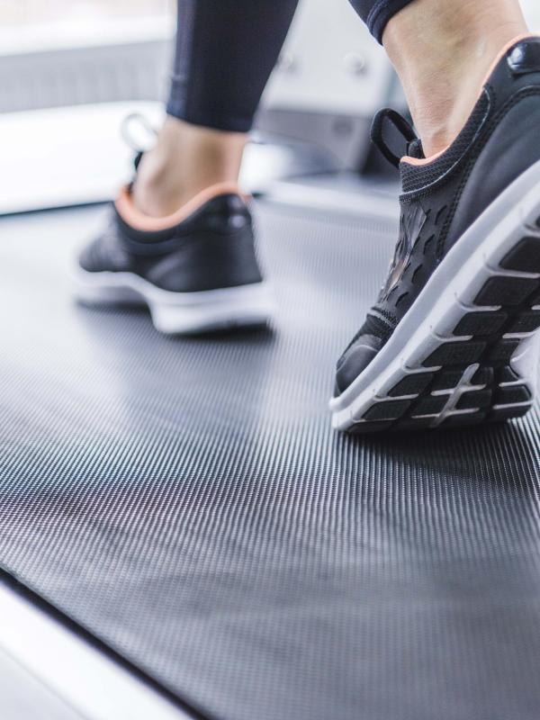 woman wearing sneakers walks on treadmill