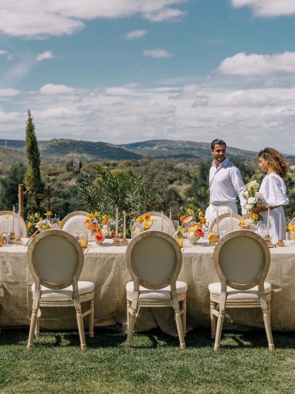couple walking along a table set for a wedding outside