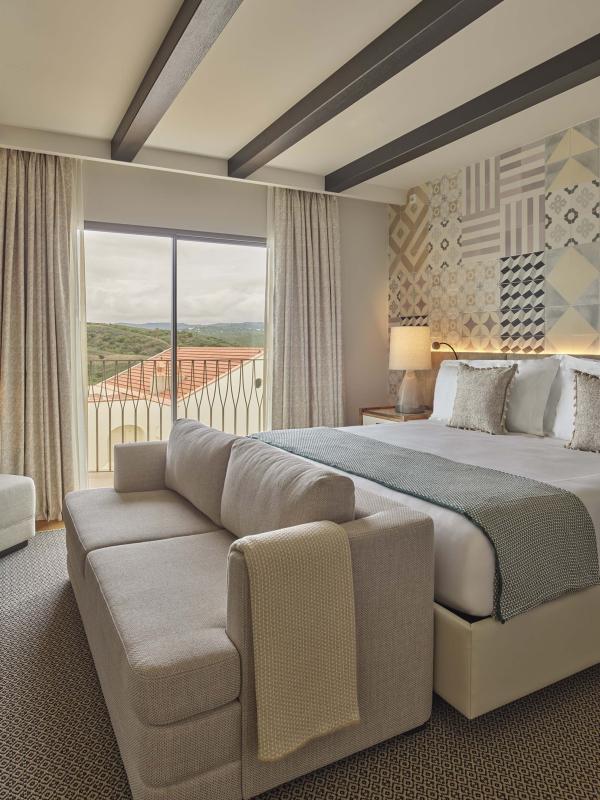 Bedroom with sofa at the foot of the bed and a small chair