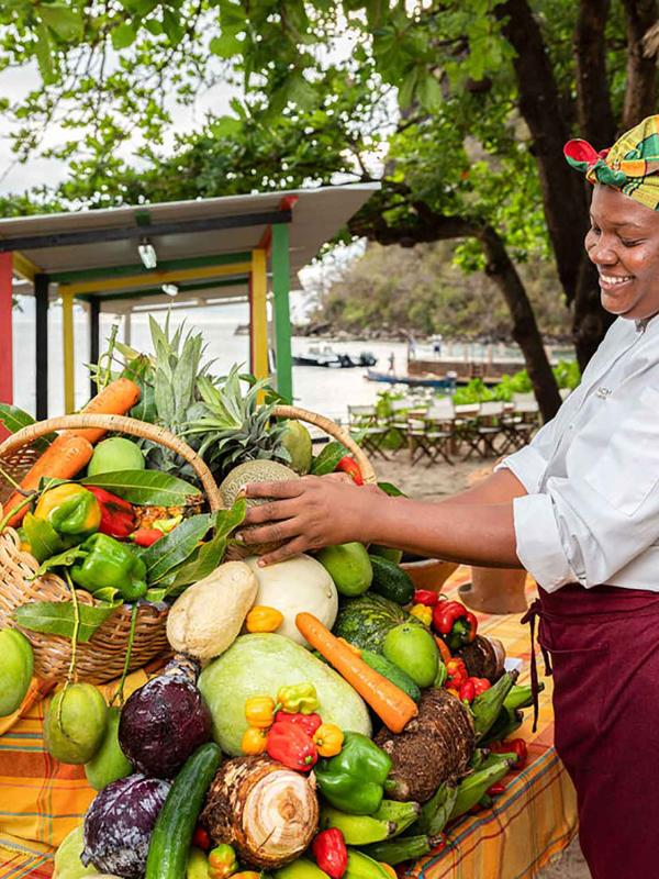 A woman staking fruit and vegetables at a stand
