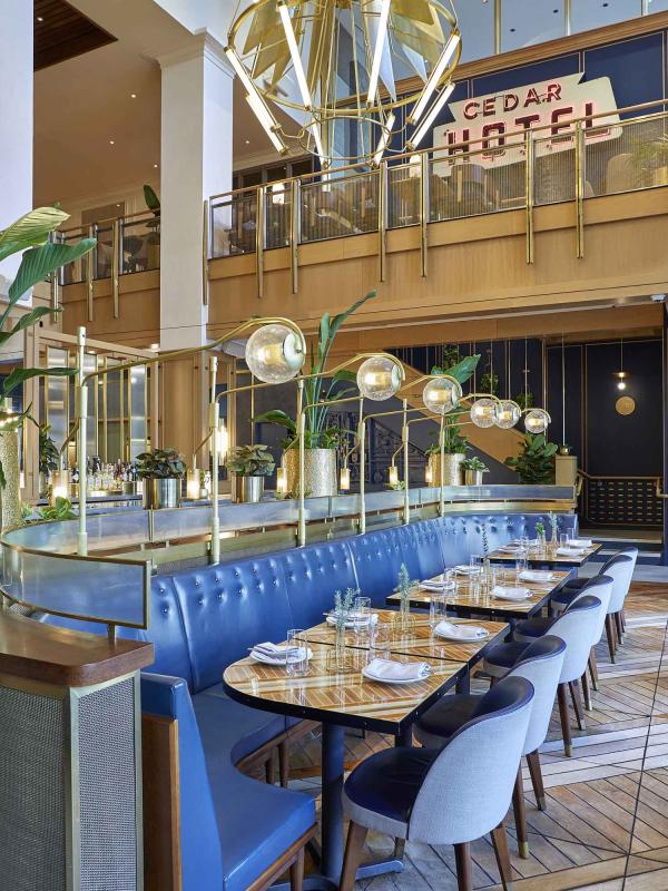 The dining room of Sommerset, Viceroy Chicago, with large blue benches and a wall-to-wall bar