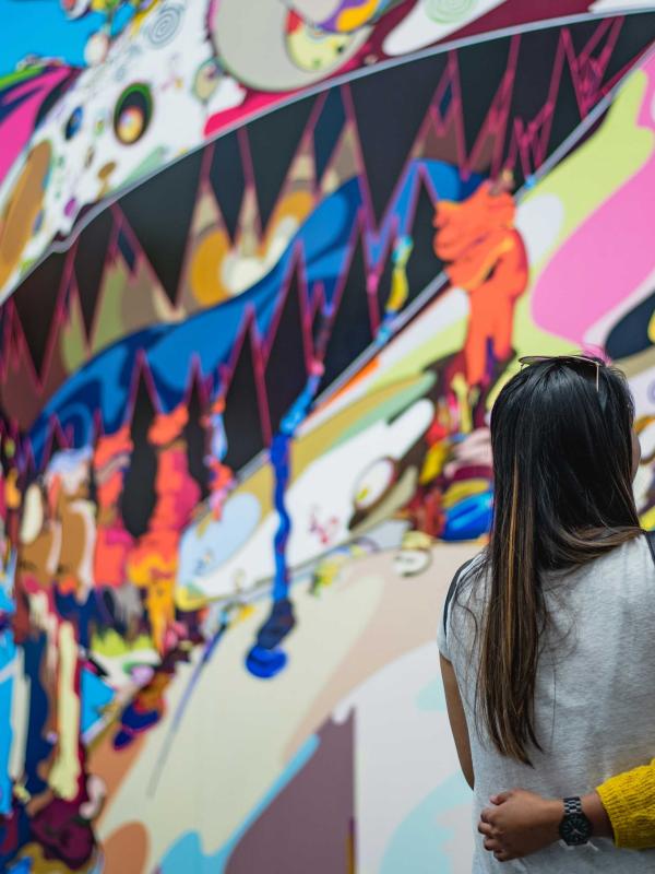 Two visitors to Chicago, arm in arm, appreciate a large street art mural
