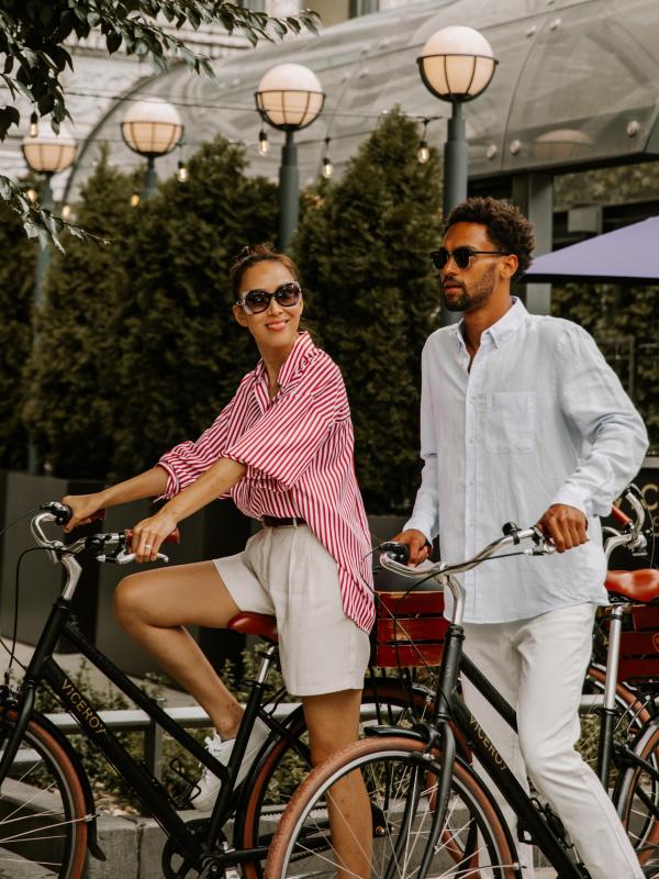 A couple rides bicycles in downtown Chicago near the Viceroy Chicago entrance