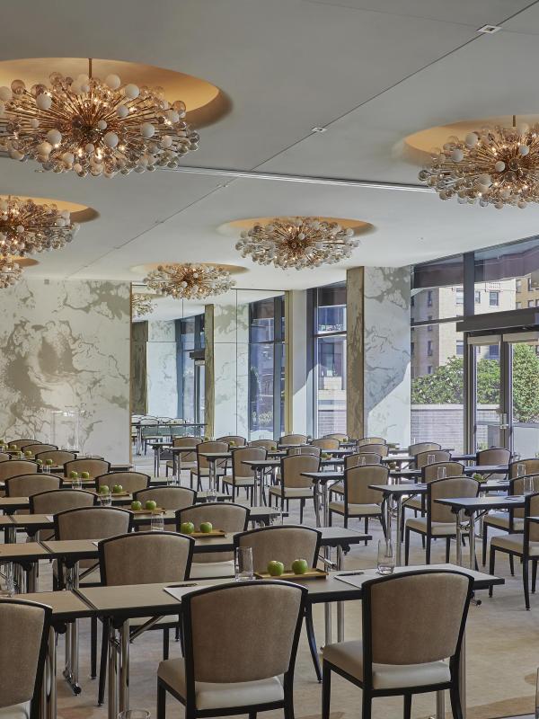 A long meeting room with rows of desk under a set of ornate pendant lights at Viceroy Chicago