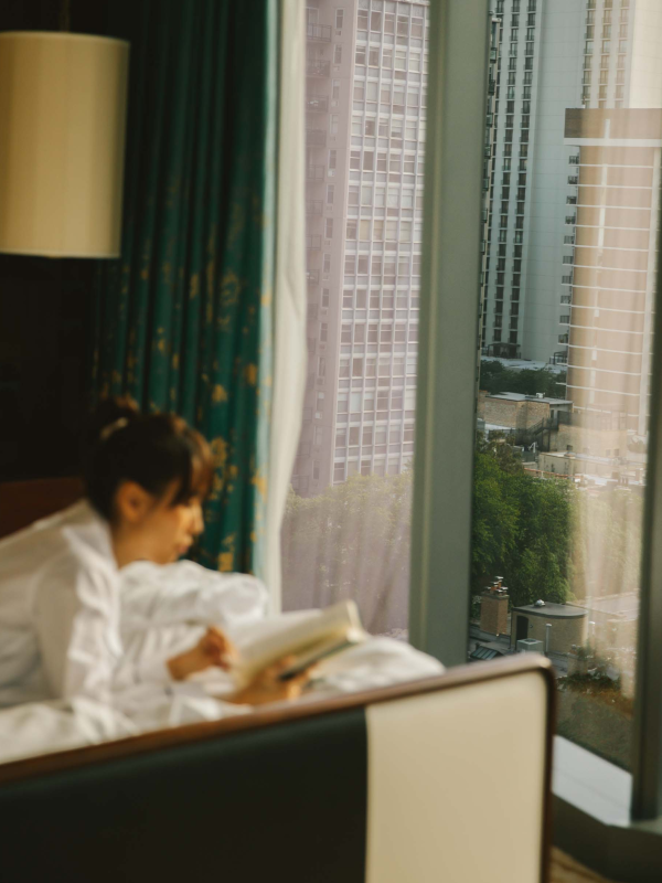 A woman laying on a bed reading a book at Viceroy Chicago